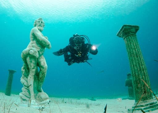 Scuba diver exploring submerged statue ruins in Mediterranean