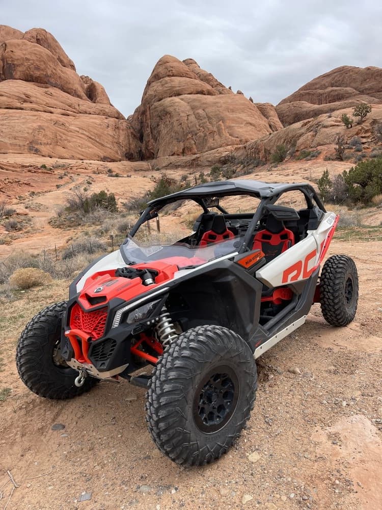 Red side-by-side rock buggy navigating rocky desert terrain off-road ride