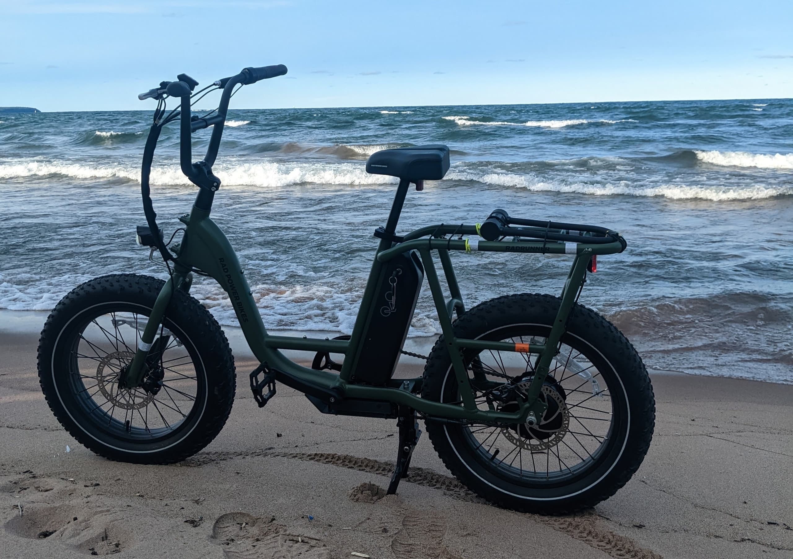 Electric fat-tire bike parked on sandy beach by waves