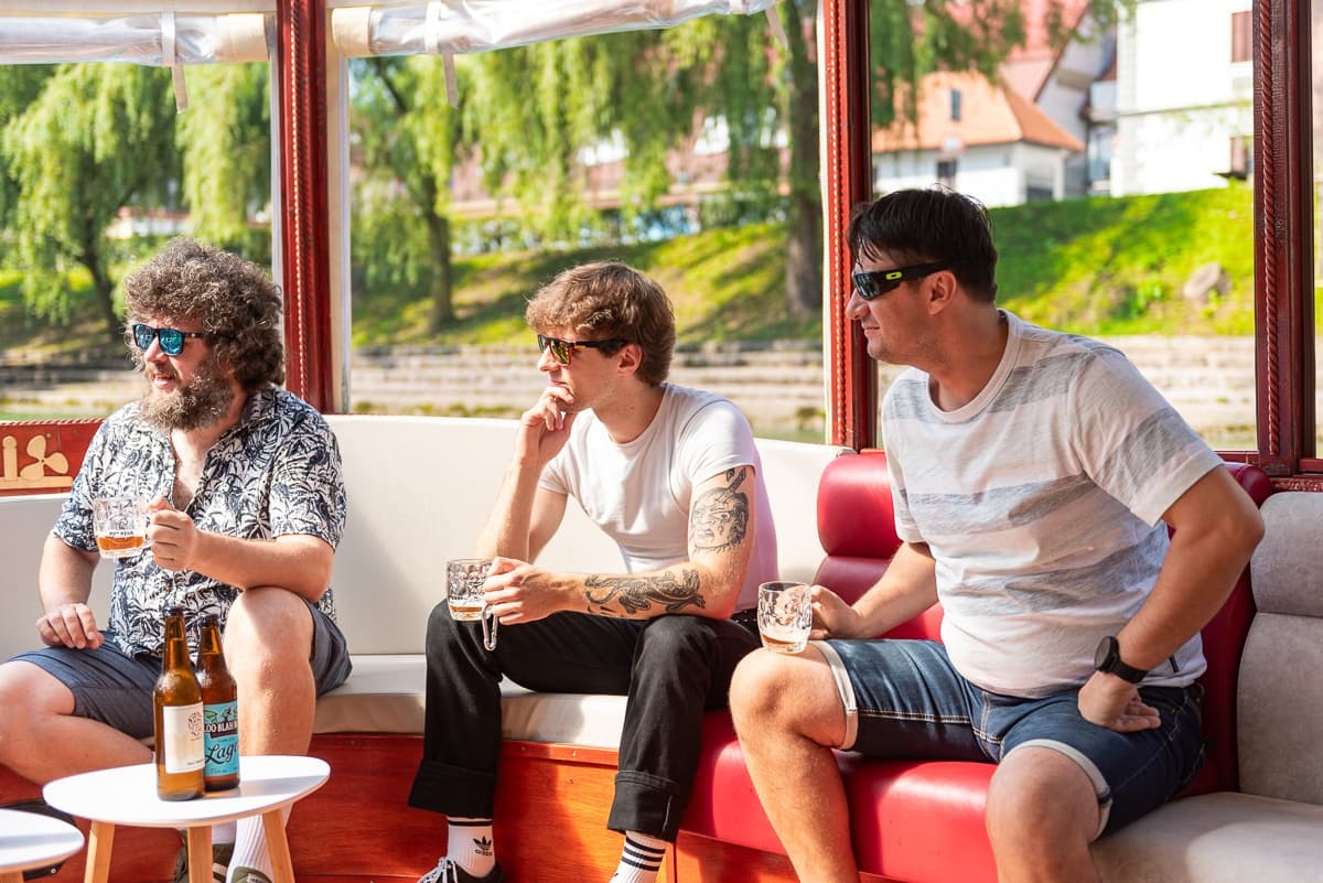 Casual friends relaxing with beers aboard a sunny riverboat cruise