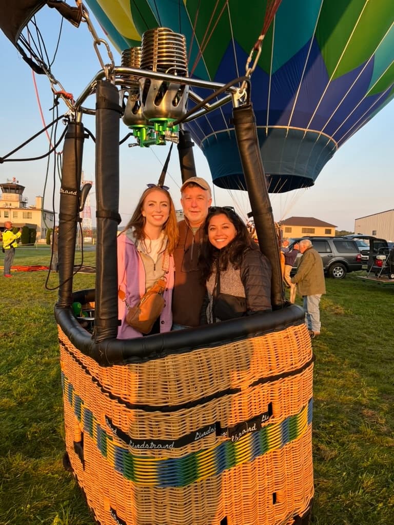 Passengers smiling in hot air balloon wicker basket at sunrise launch