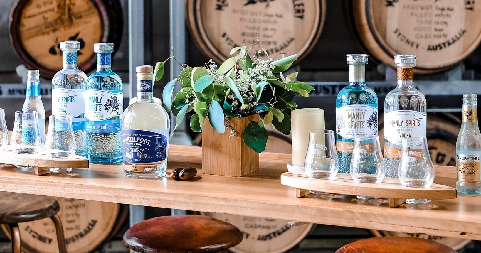 Gin bottles on wooden bar with barrel-aged cask backdrop in tasting room