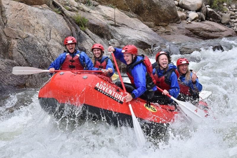Whitewater rafters navigating rocky mountain river rapids