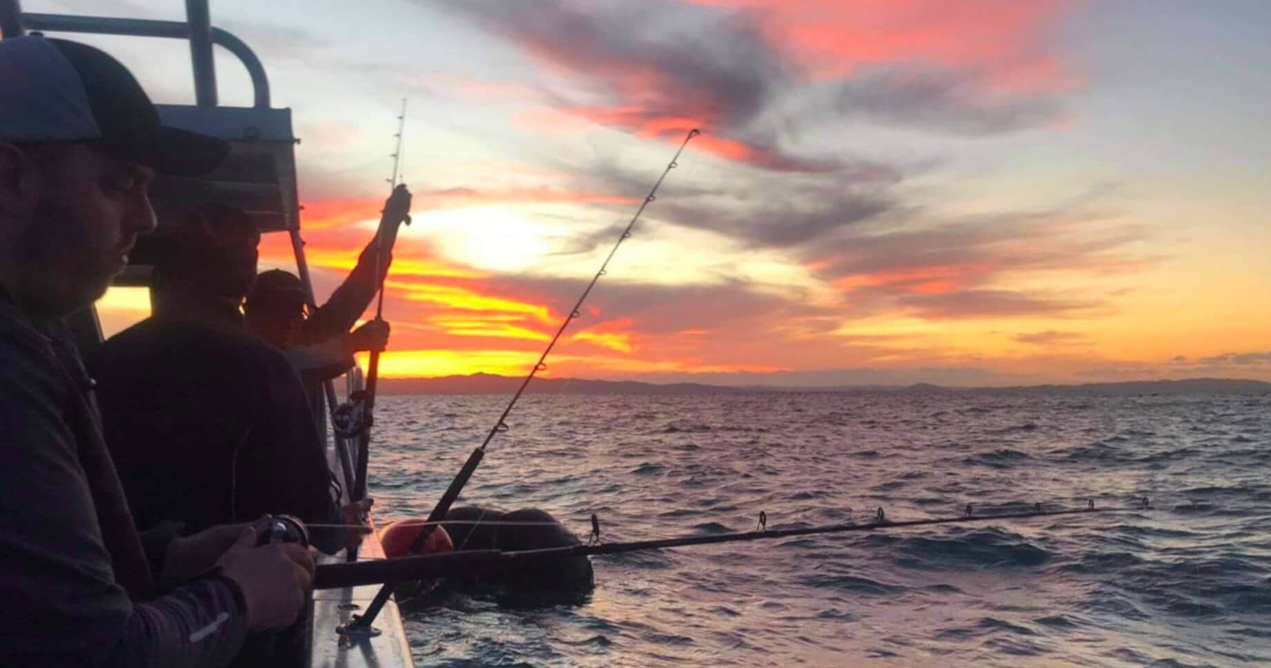 Anglers deep-sea fishing at sunset on open ocean charter