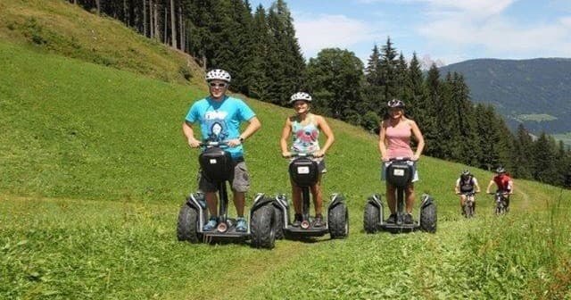 Segway riders touring alpine meadow trails with pine forest views
