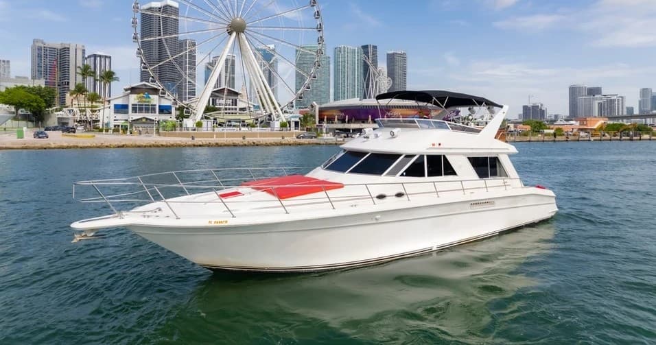 Motor yacht cruising by waterfront skyline and Ferris wheel