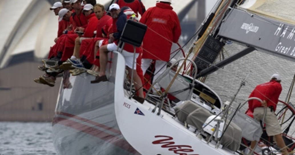 Sailboat racing with crew trimming sails on open harbor waters