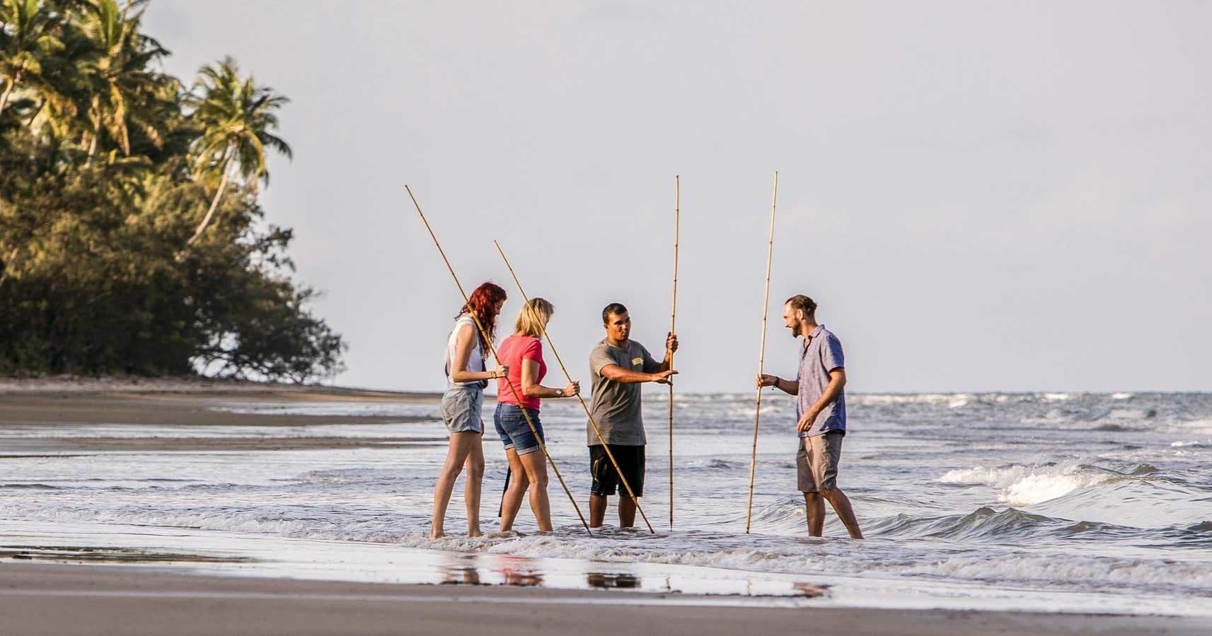 Friends practicing traditional fishing on sandy shoreline