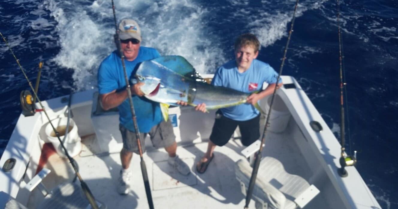 Father and son anglers posing with caught mahi mahi on offshore boat