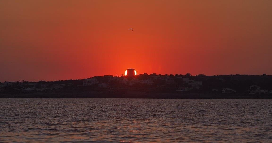 Sunset over coastal Menorca with calm sea horizon view