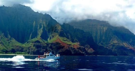 Tour boat cruising turquoise water below dramatic cliffs