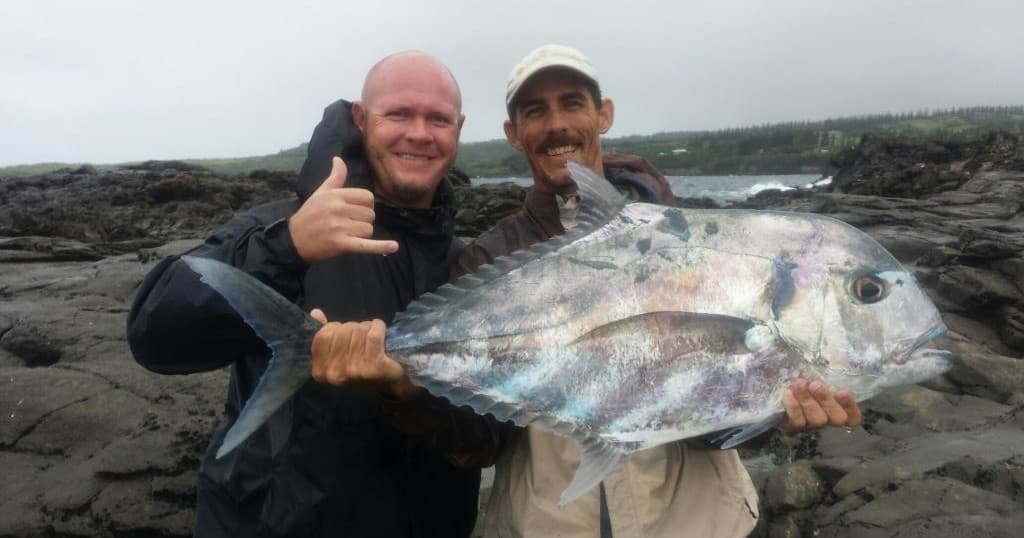 Shore anglers holding large catch on rocky Maui coastline