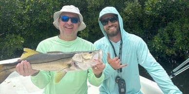 Two anglers on a charter boat displaying large fish catch