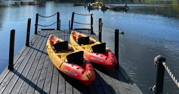 Two kayaks moored at wooden dock on serene lake shore