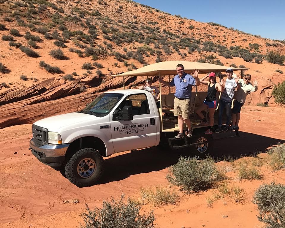 Guided jeep tour with visitors on desert trail near canyon