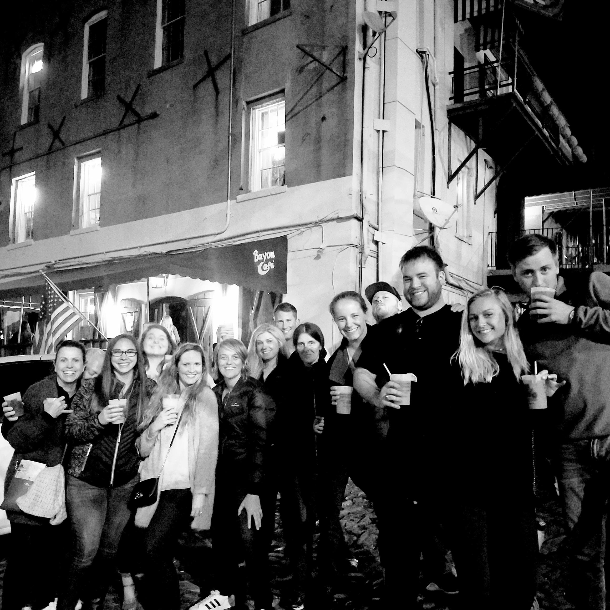 Friends on nighttime walking pub tour along Savannah cobblestone street