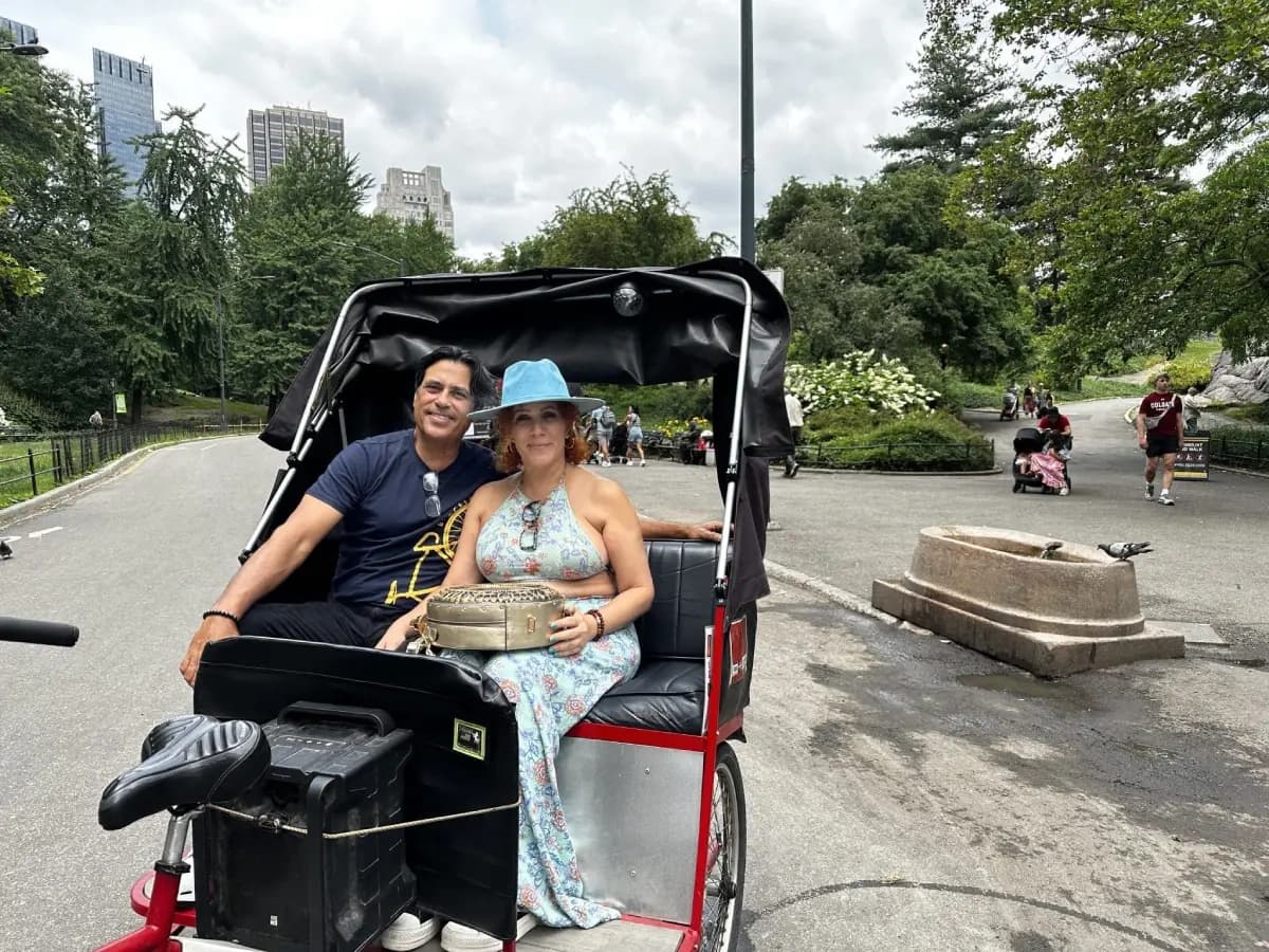 Couple on pedicab tour through Central Park paths, smiling