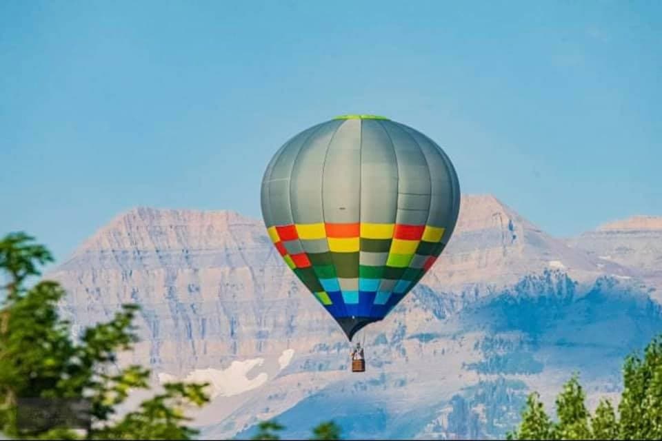 Hot air balloon floating over Utah mountain landscape at sunrise