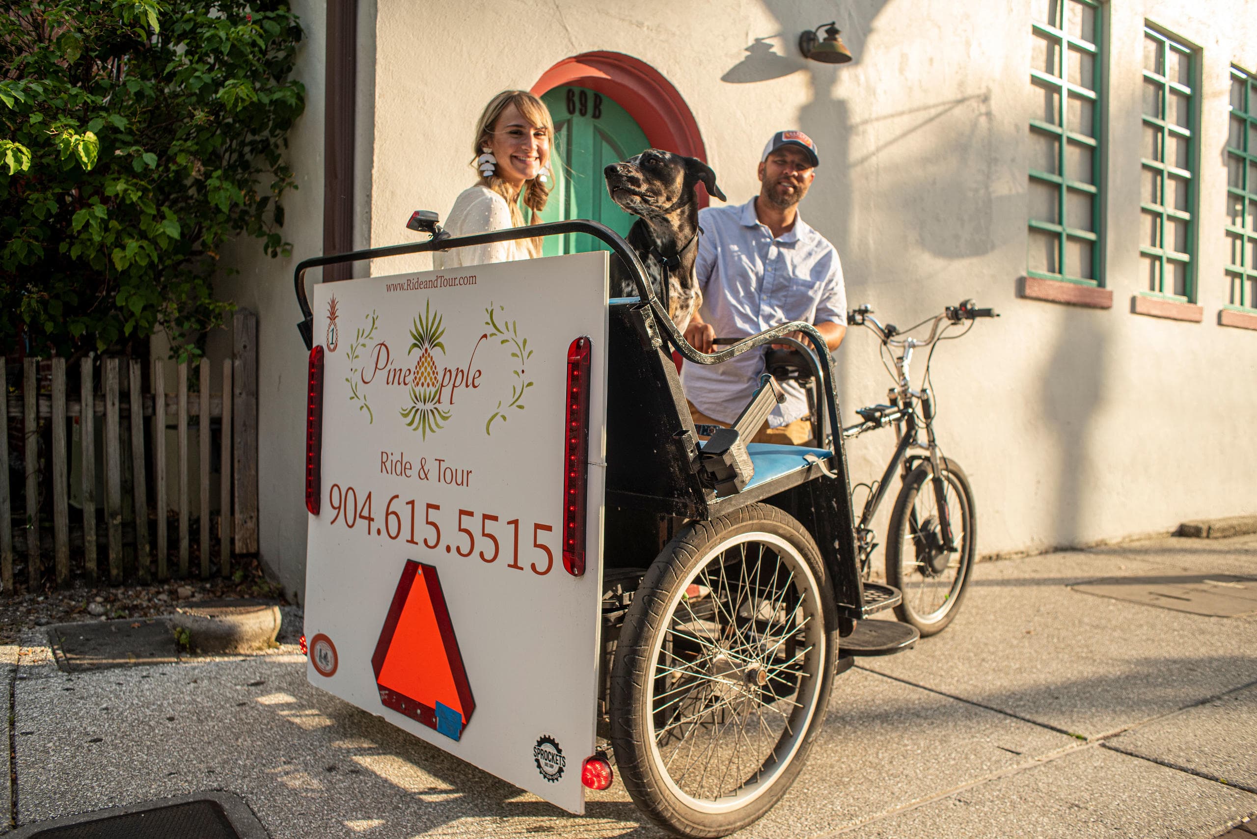Daytime pedicab tour with driver, passengers and small dog in plaza