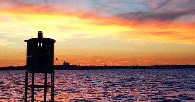 Vibrant sunset over coastal navigation post on calm sea