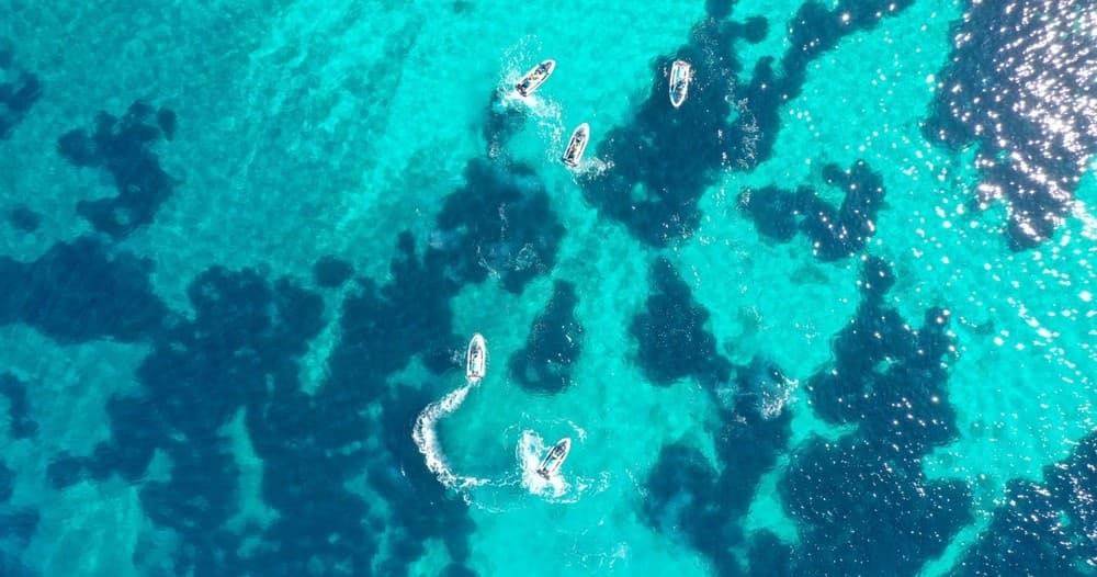 Aerial view of turquoise sea with jet skis near reefs