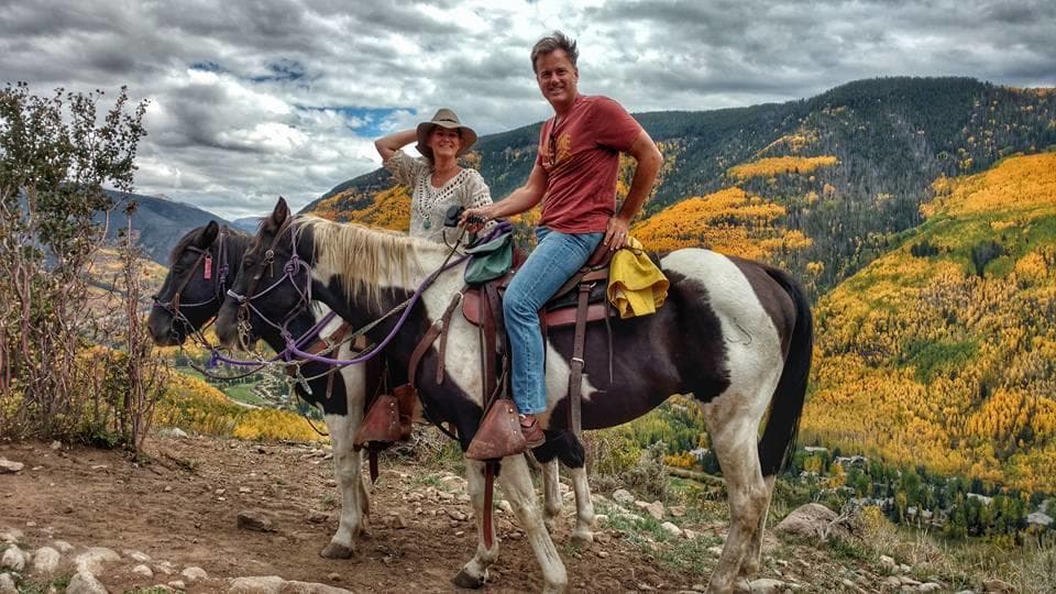 Couple horseback riding amid autumn aspen and mountain views