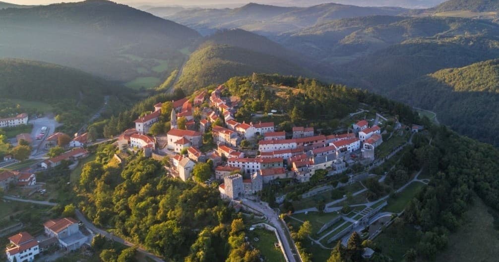 Aerial view of hilltop medieval town and rolling forested hills