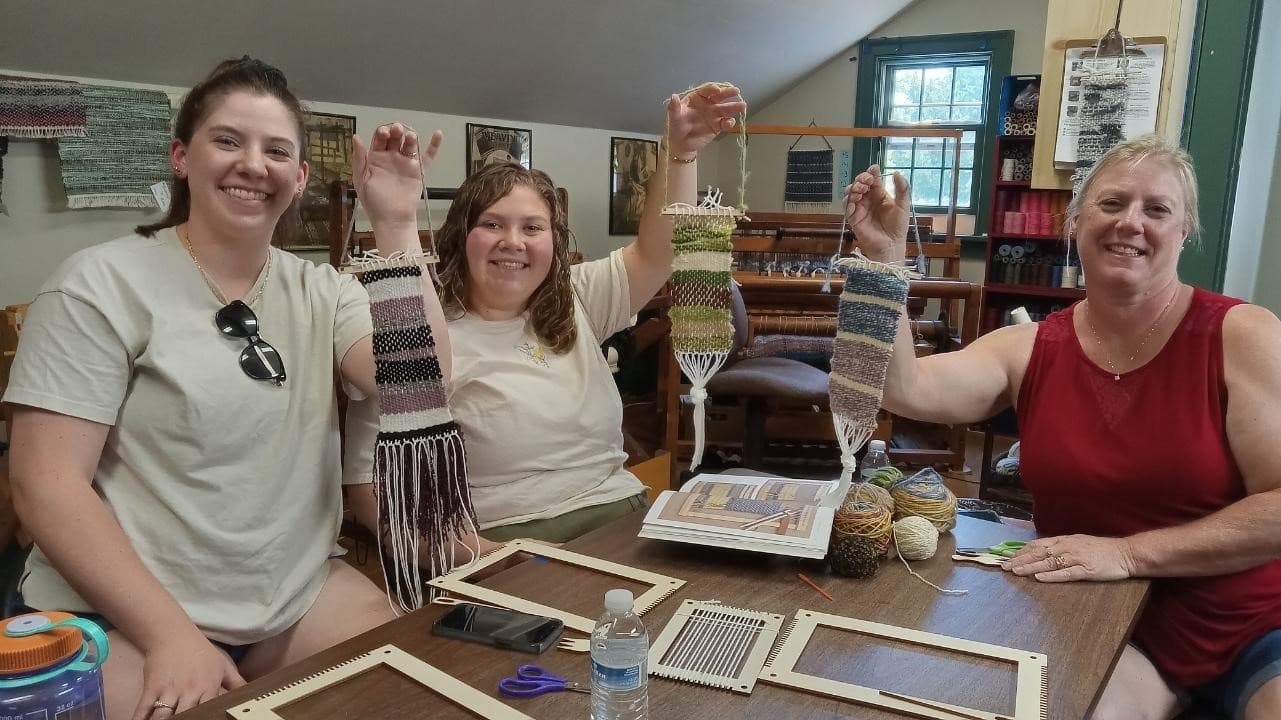 Women weaving handwoven scarves in indoor fiber arts workshop