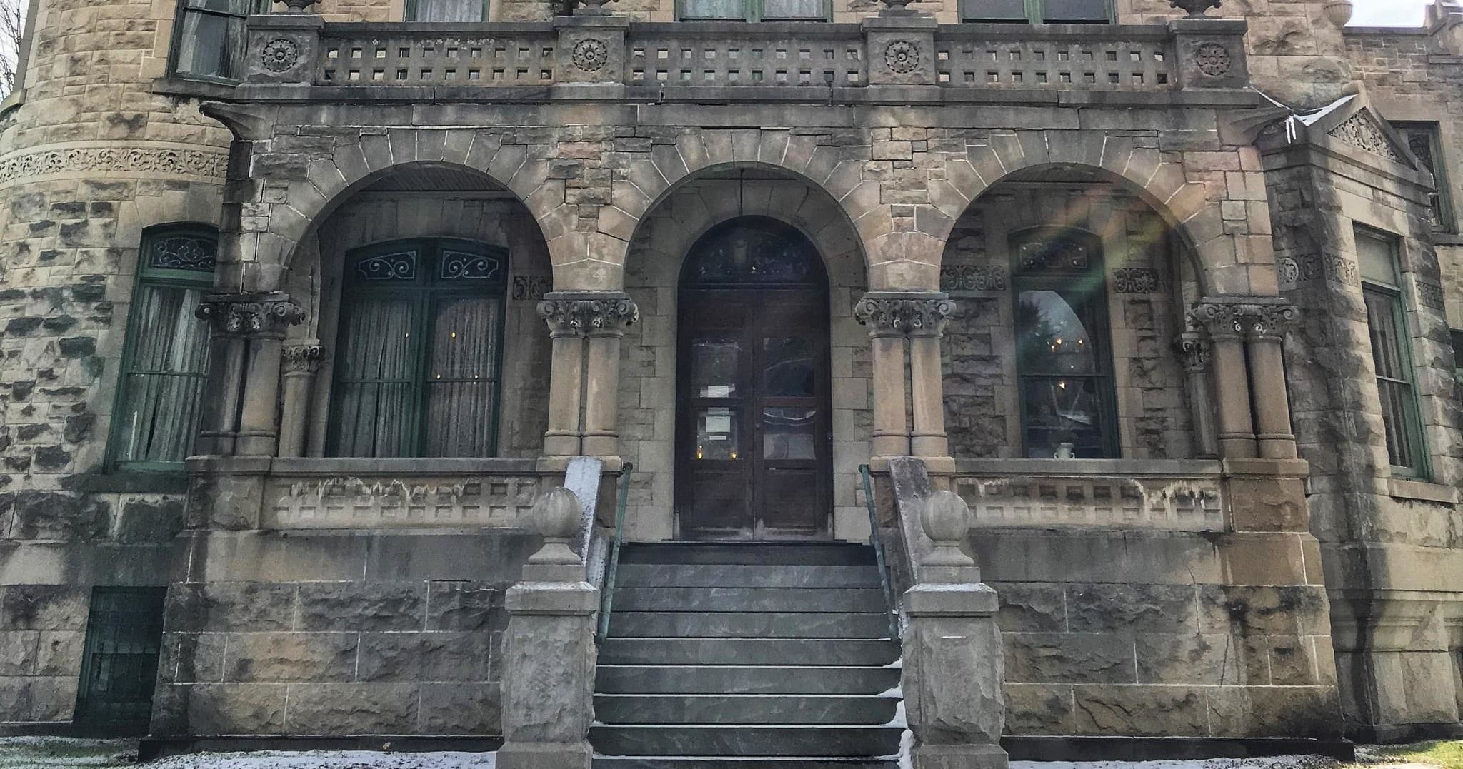 Stone mansion entrance with steps and arched doorway, exterior visit