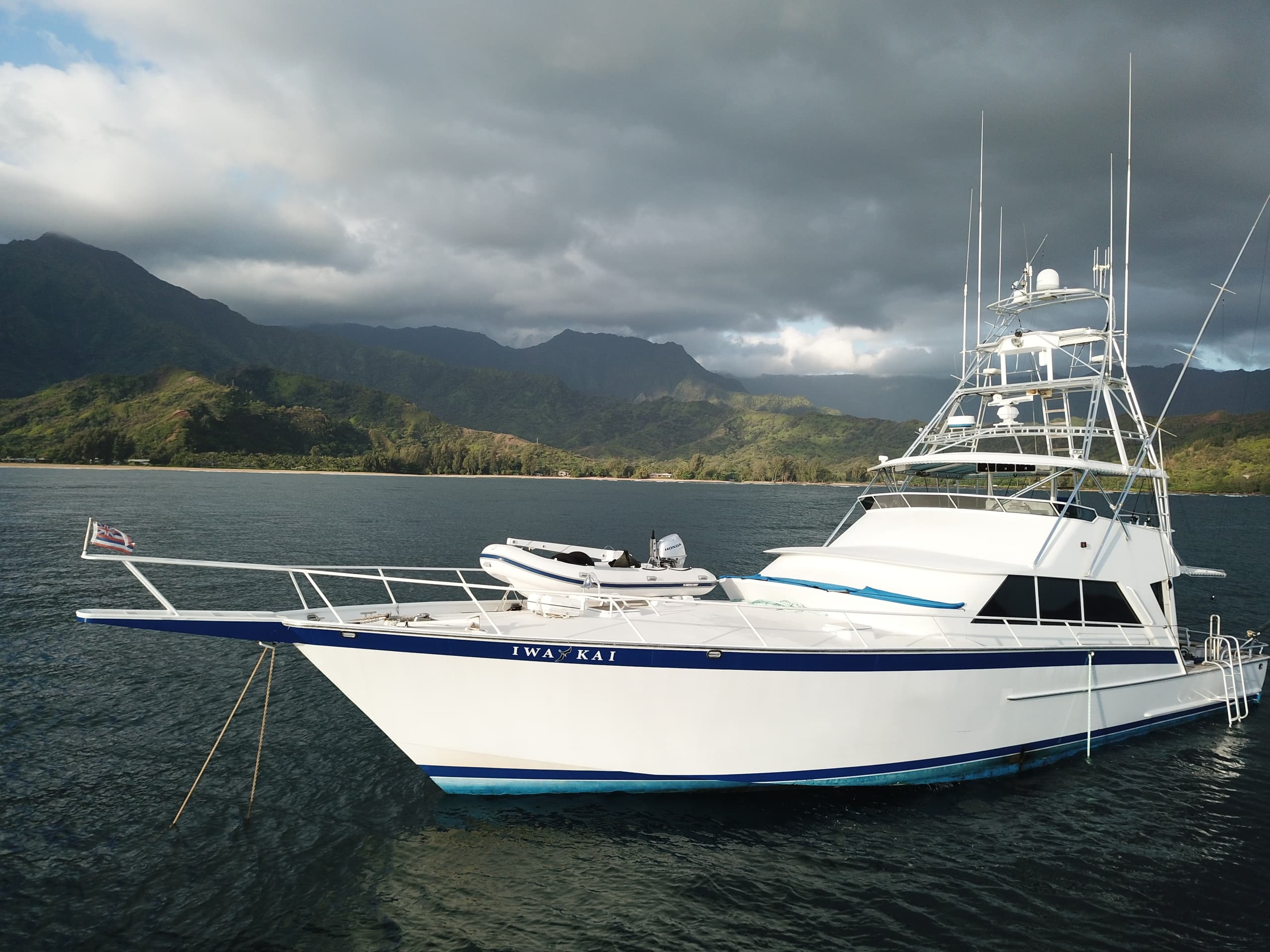 Anchored charter yacht against moody mountains and dramatic cloudy sky