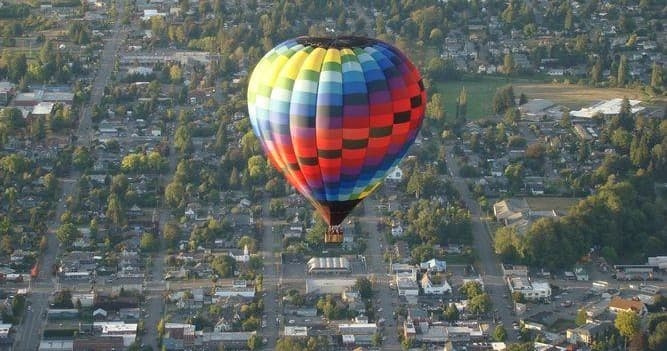 Hot air balloon floating over suburban cityscape aerial view
