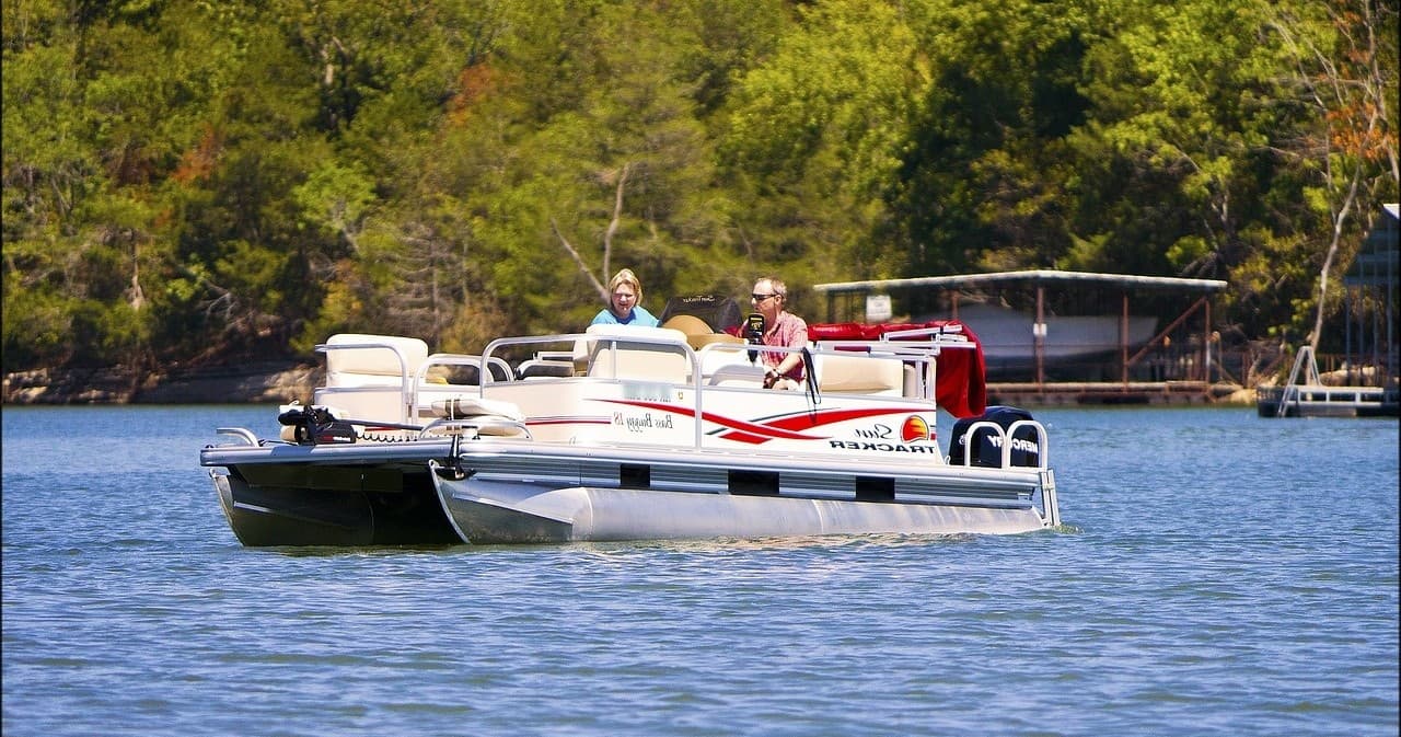 Pontoon boat anchored on calm lake with forested shore backdrop