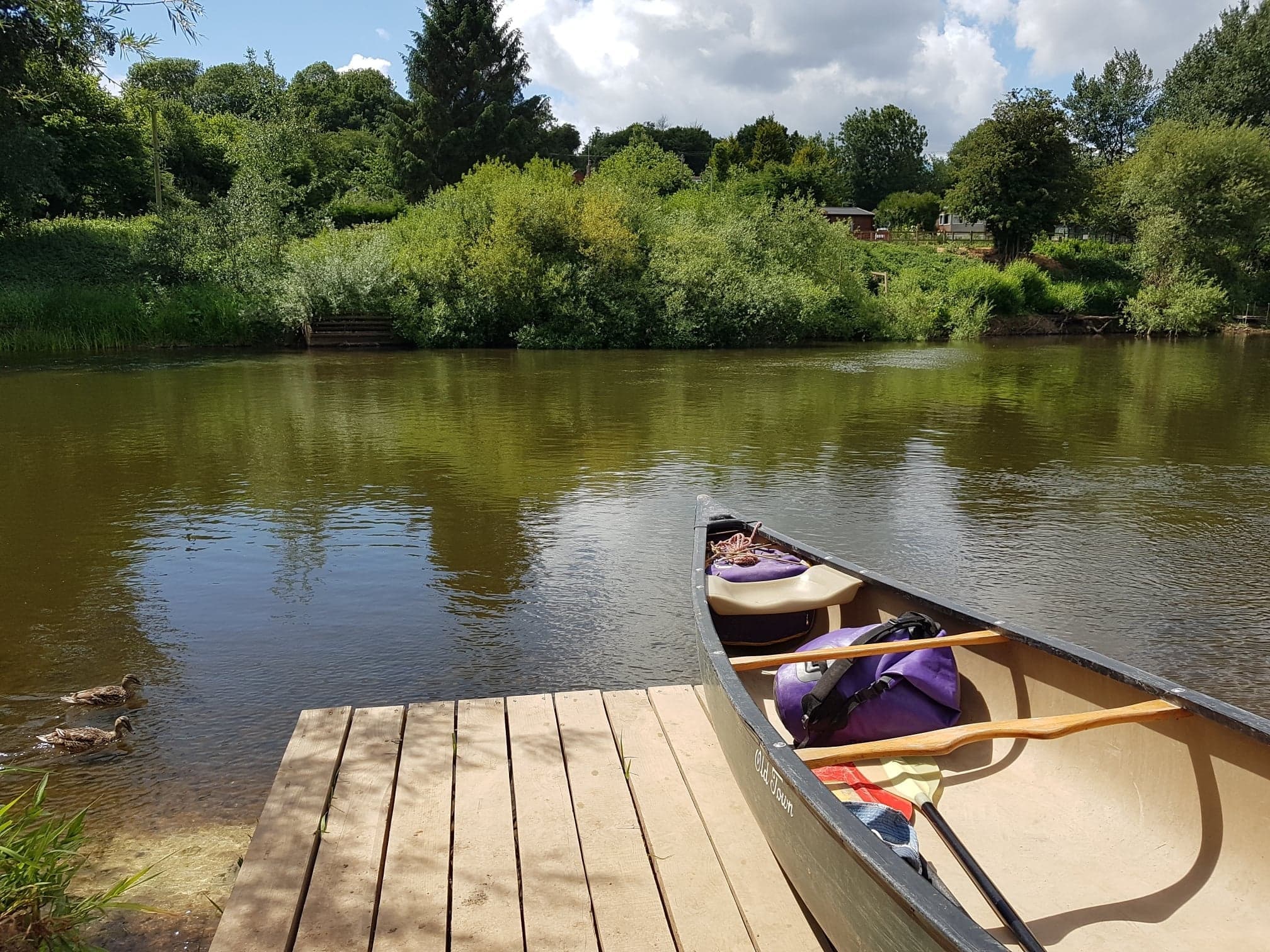 Canoe docked on calm River Severn with green riverside views