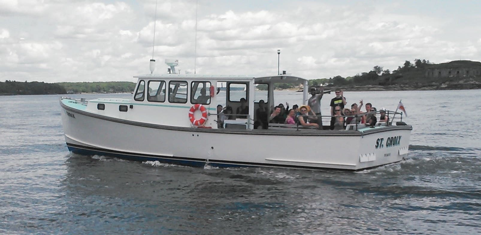 Small coastal tour boat carrying passengers on calm ocean waters near island