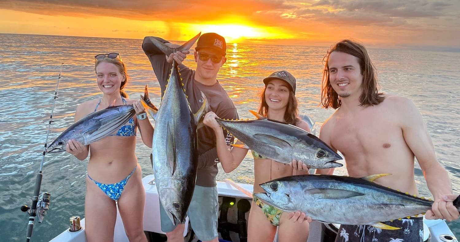 Anglers holding yellowfin tuna at sunset off Rincon shore