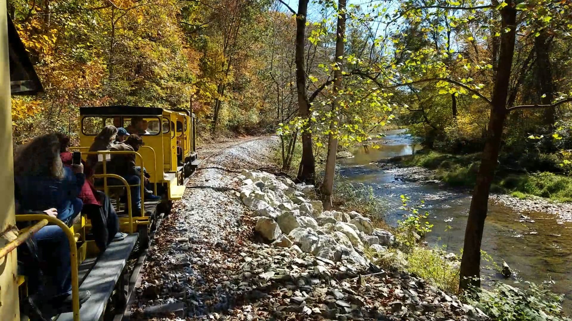 Open-air scenic train riding beside autumn river gorge