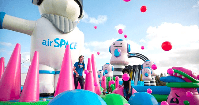 Participants on large inflatable obstacle course under blue sky