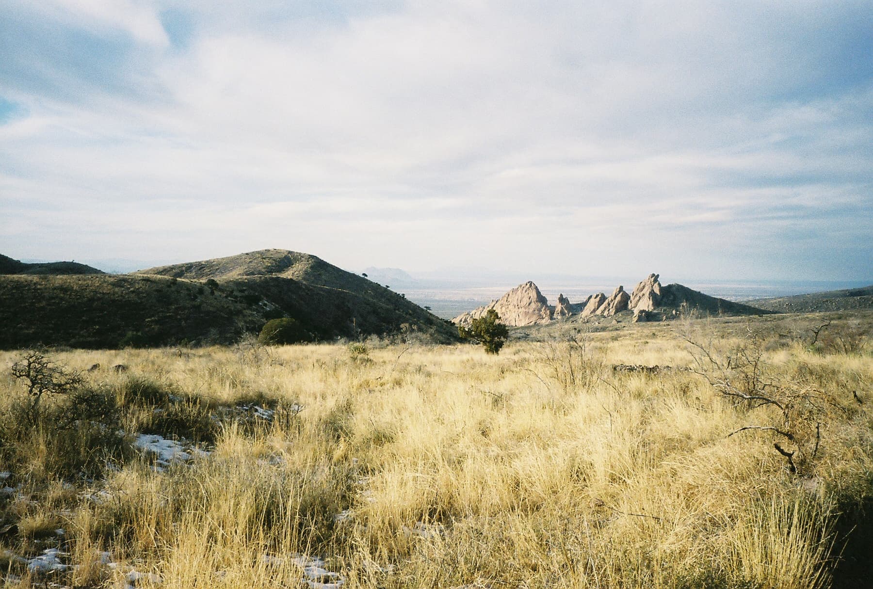 Scenic grassland foothills with rocky outcrops, ideal for hiking