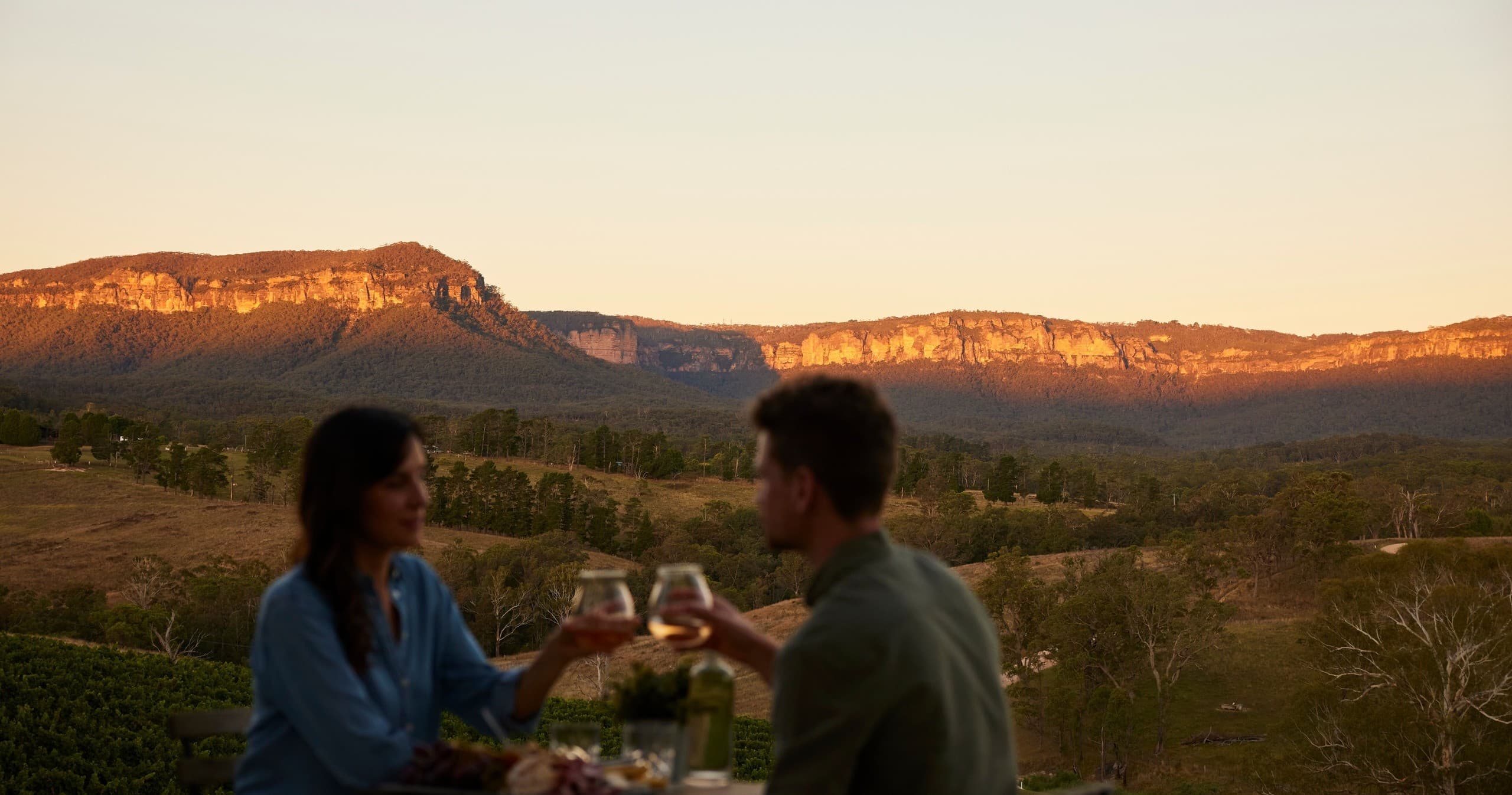 Couple enjoying sunset wine with mountain valley views in Blue Mountains