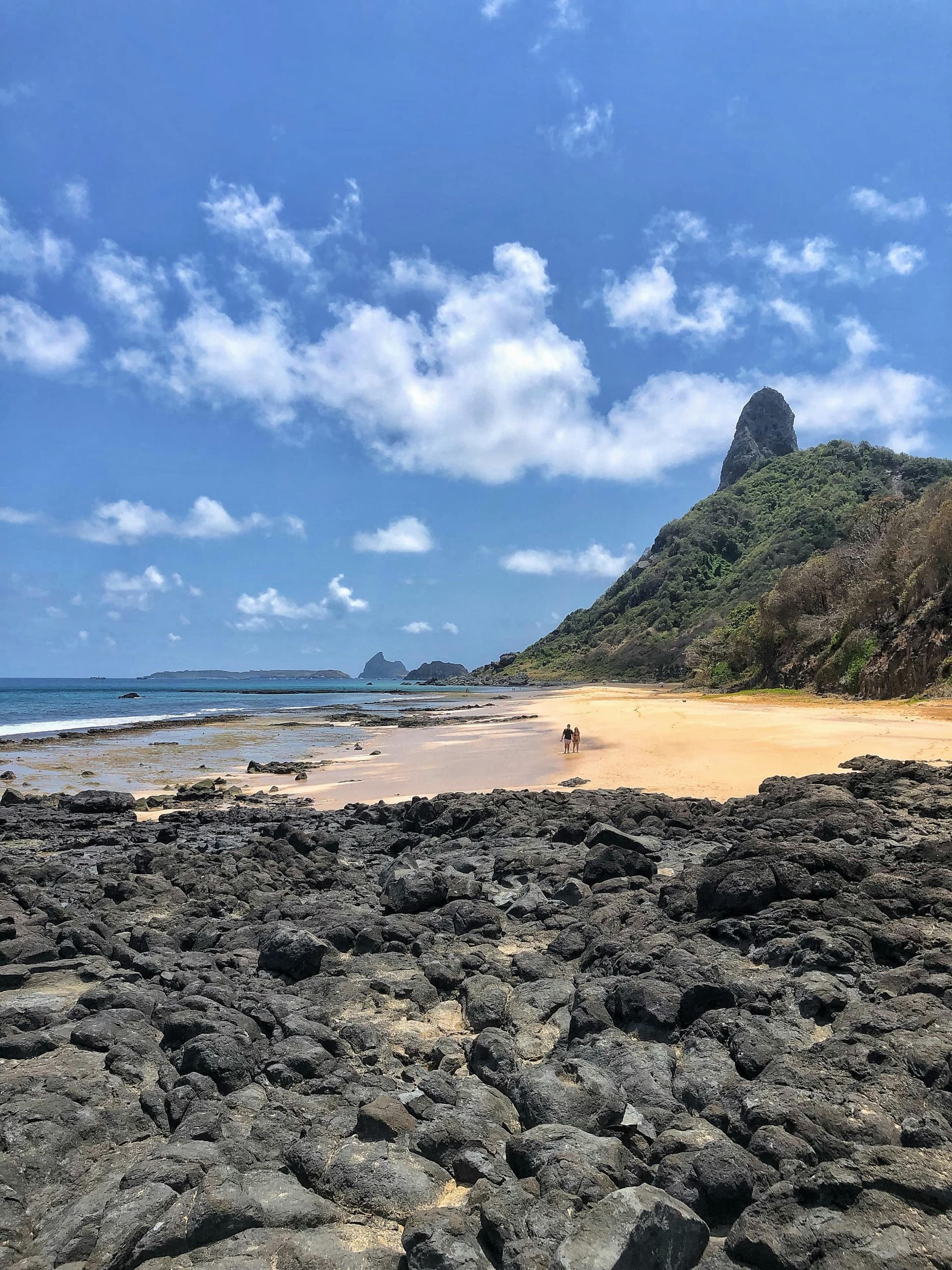 Hikers on volcanic beach with rocky foreground, Azores coast