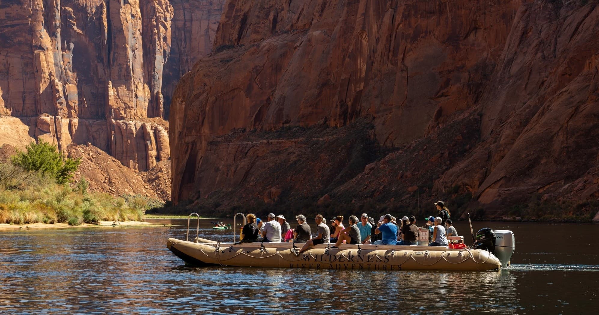 Scenic motor-raft floating in wide canyon river with cliffs