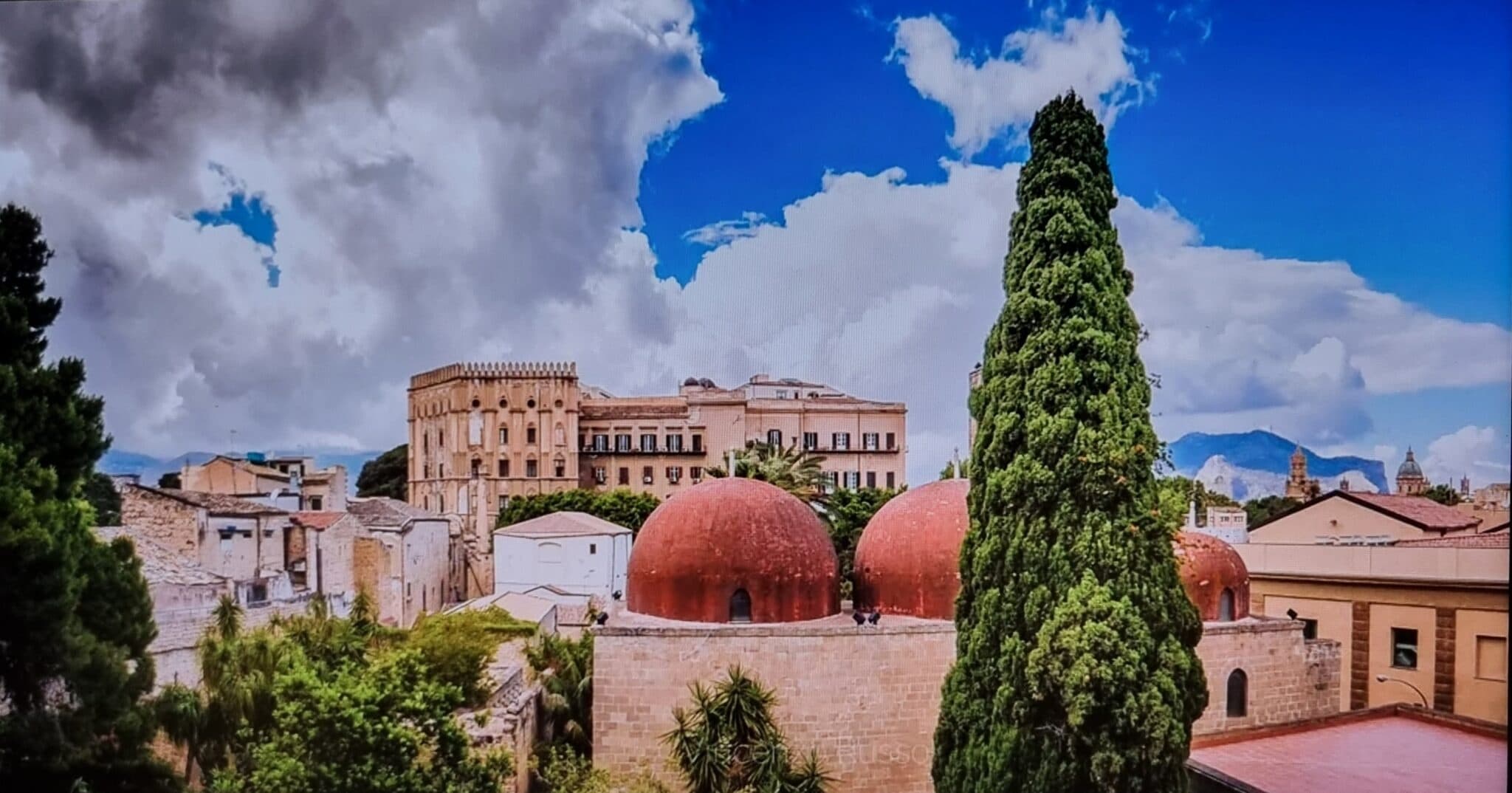 Historic cityscape with red domes and cypress trees skyline