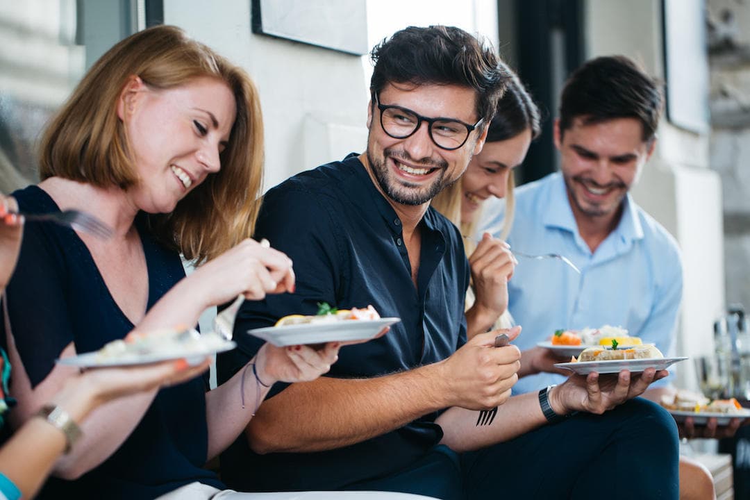 Group sharing plated Polish dishes at sunny outdoor dining