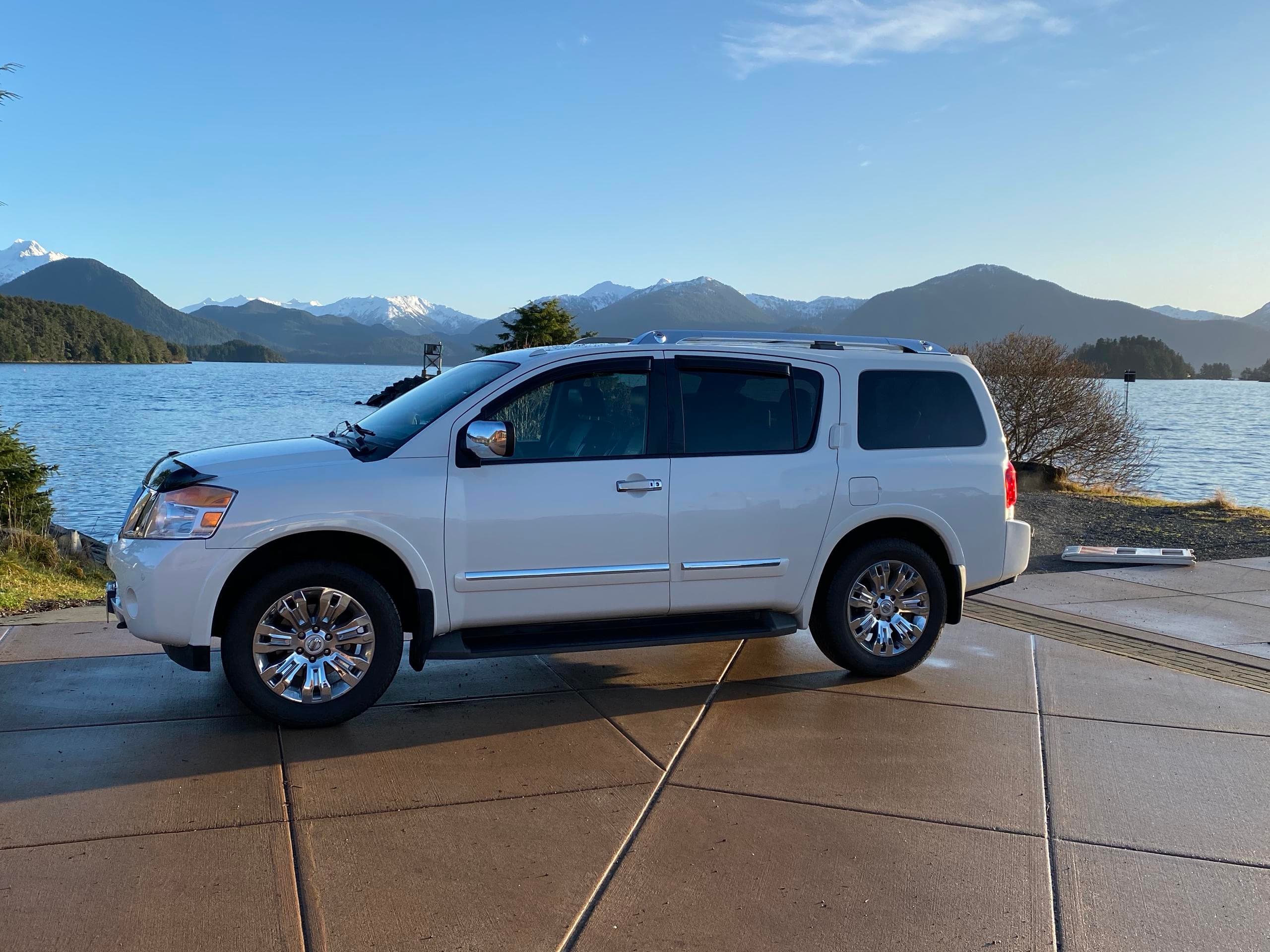 White tour SUV parked by Sitka waterfront with mountain views