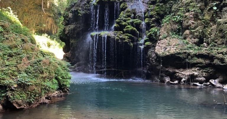 Waterfall cascading into clear forest pool, scenic swimming spot