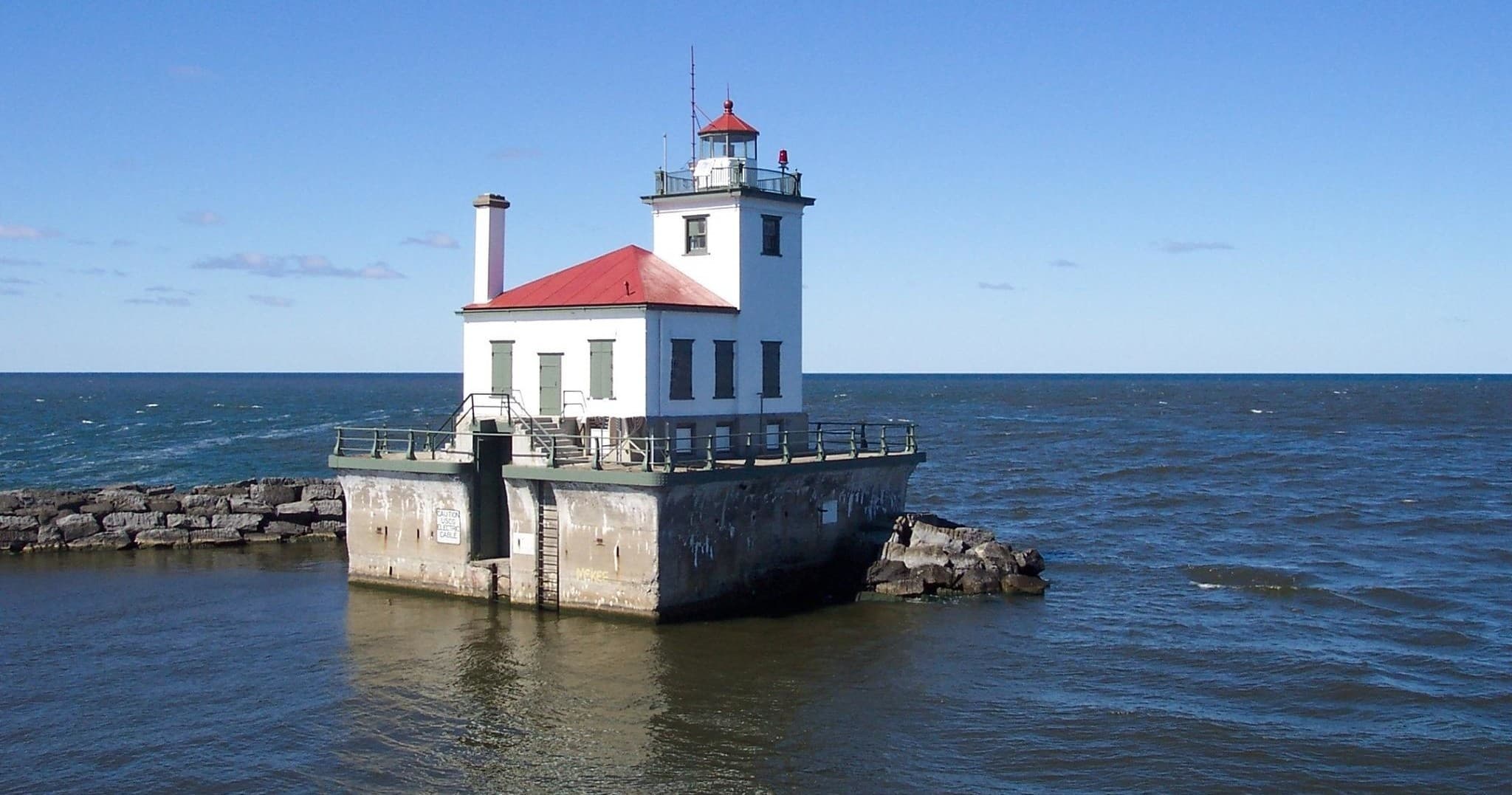 Coastal lighthouse on pier overlooking open lake waters, scenic visit