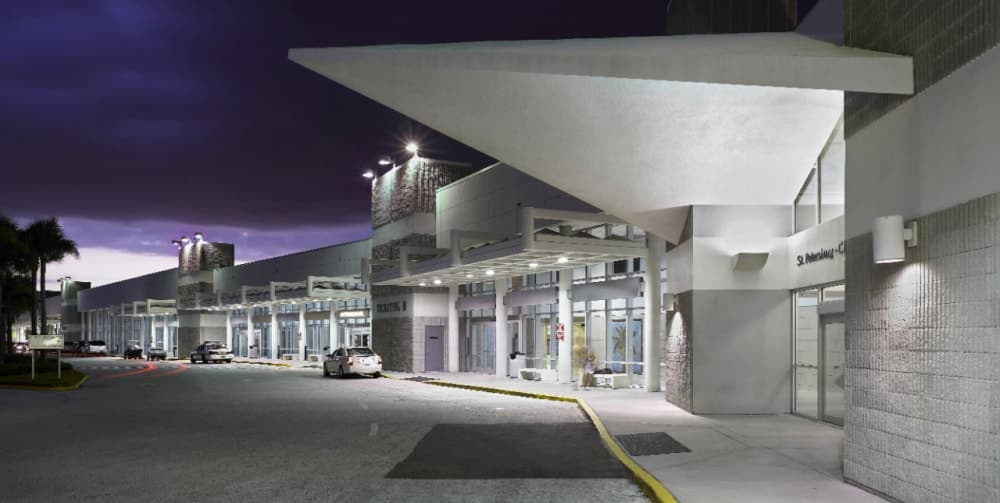 Airport terminal exterior curbside drop-off under canopy at night
