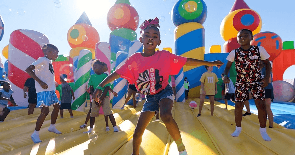 Kids dancing on giant outdoor bouncing castle at sunny event