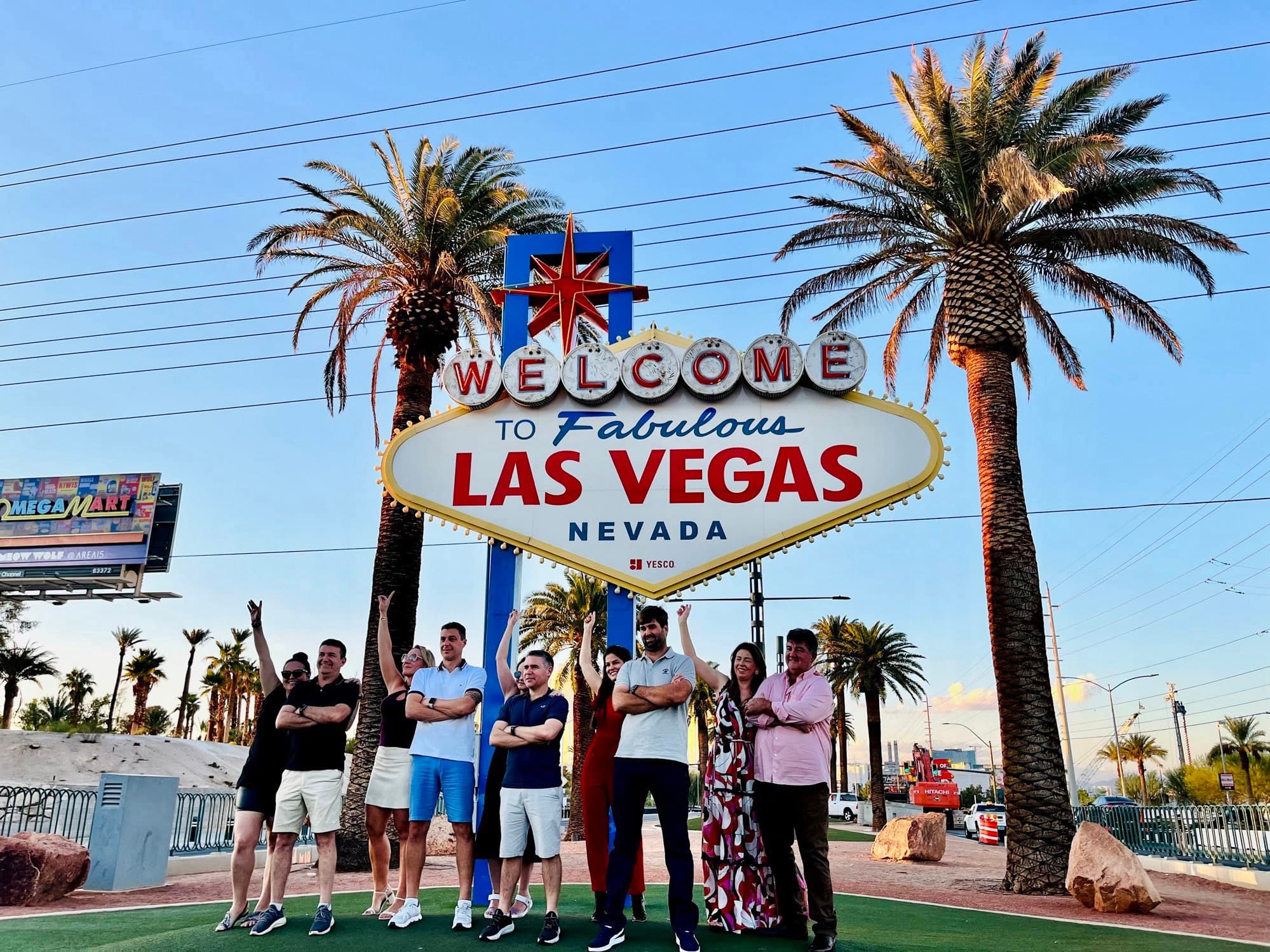 Tour group posing at Welcome to Las Vegas sign with palms