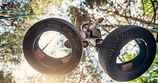 Tire swing hanging over reflective lake at rustic camp